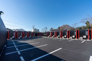 Un estacionamiento con filas de edificios portátiles, cada uno con un marco rojo y una pequeña ventana.