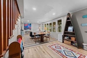 Uma sala de jantar com mesa e cadeiras de madeira, um tapete e uma estante de livros.
