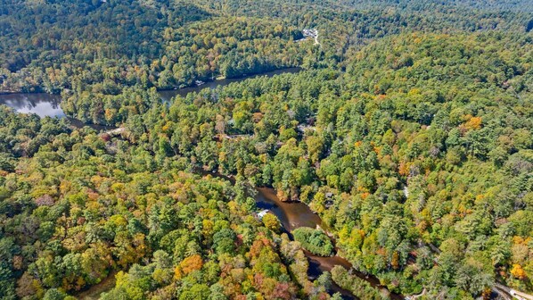 An aerial view of a forested area with a river, a road, and a building.