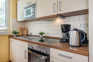 Eine moderne Küche mit Mikrowelle, Kaffeemaschine, Wasserkocher und Backofen.