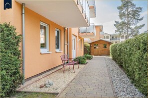 A building with a paved pathway, a bench, and a wooden structure.
