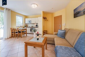 A compact living space with a dining area, kitchenette, and a sofa with a cushion.