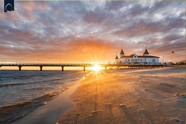 Eine Küstenlandschaft mit einer Brücke, einem Strand und einem Gebäude mit zwei Türmen.