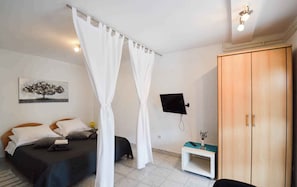 A bedroom with a bed, a bedside table with a plant, a wardrobe, and a wall-mounted TV. - Apartments Pjescana Uvala/istrien 11044 (Medulin)