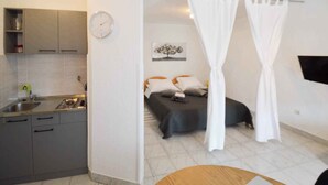 Una stanza con un letto, un comodino, una sveglia e una finestra con tende.