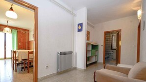 Un soggiorno con un divano, un'area pranzo con tavolo e sedie, e una cucina visibile tramite un'apertura.