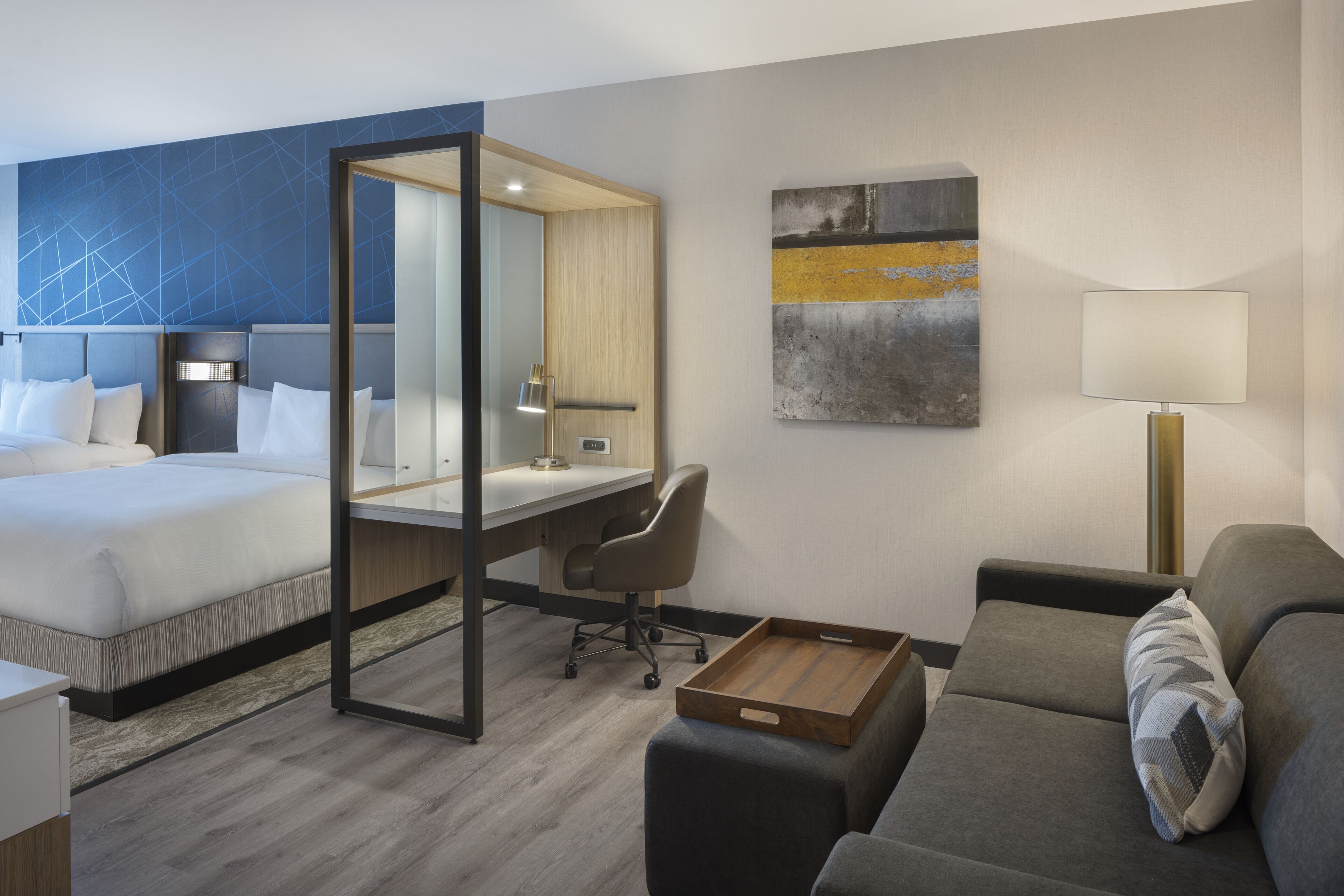 Ett hotellrum med en säng, ett skrivbord, en stol och en soffa.