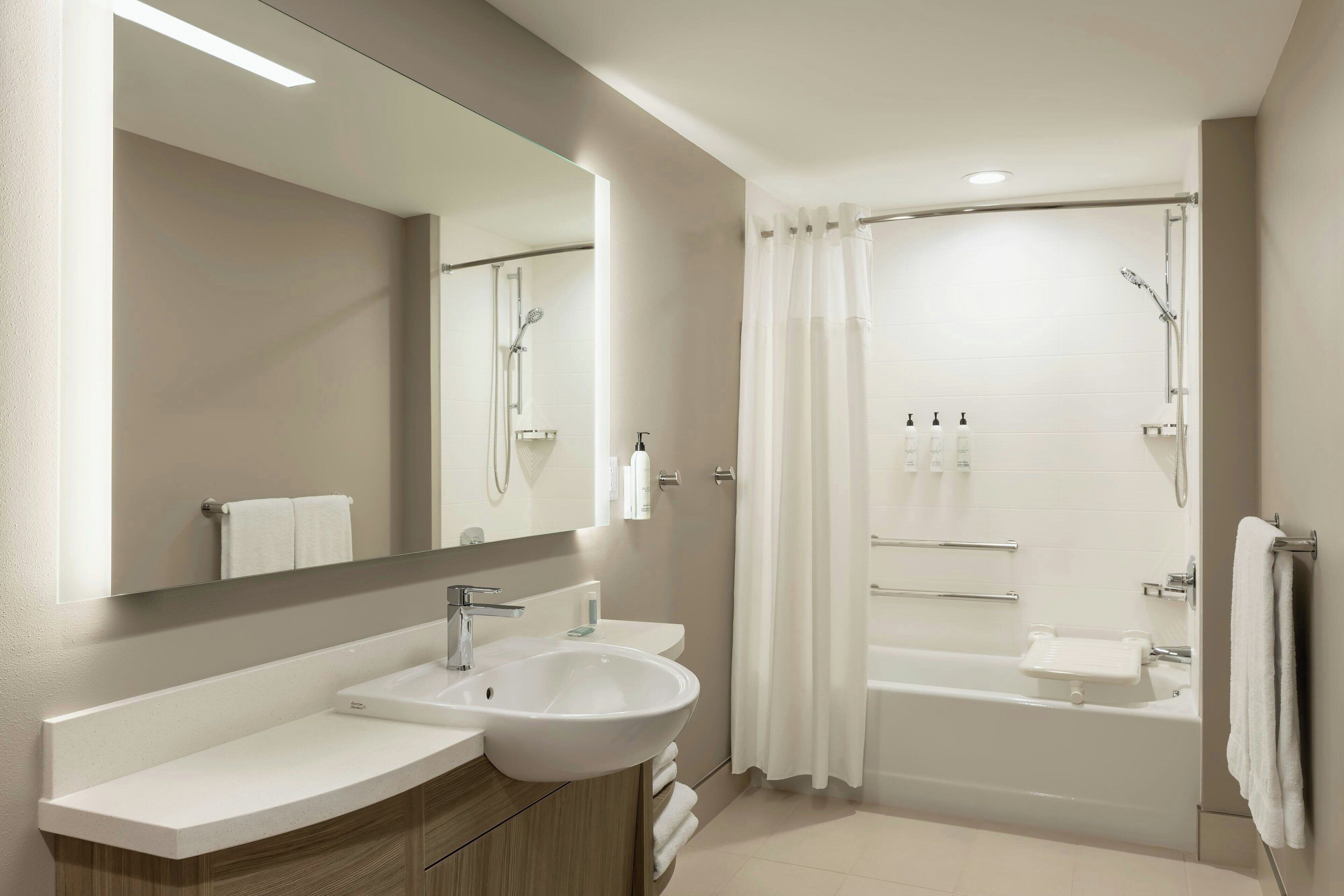 A modern bathroom with a sink, mirror, and bathtub.