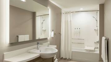A modern bathroom with a sink, mirror, and bathtub.