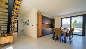 Une cuisine moderne avec des meubles de rangement aux couleurs foncées, une table à manger en bois et des chaises.