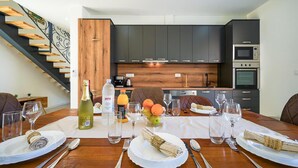 Une cuisine moderne avec des meubles de couleur sombre, un mur d’accent en bois et un four encastré.