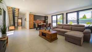Un salon moderne avec un canapé, une table basse en bois et un coin repas avec des chaises.