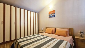 A bedroom with a bed, a nightstand, a lamp, a painting, and a wardrobe.