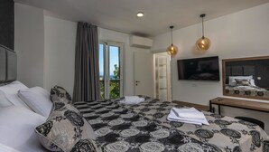 Een slaapkamer met een bed, een televisie, een bureau en uitzicht op het groen.