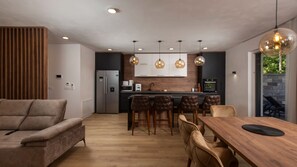 Une cuisine moderne dotée d’un îlot central, de planchers en bois et de luminaires suspendus.