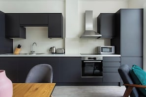 Een moderne keuken met donkere kastjes, een roestvrijstalen afzuigkap, een magnetron en een broodrooster.
