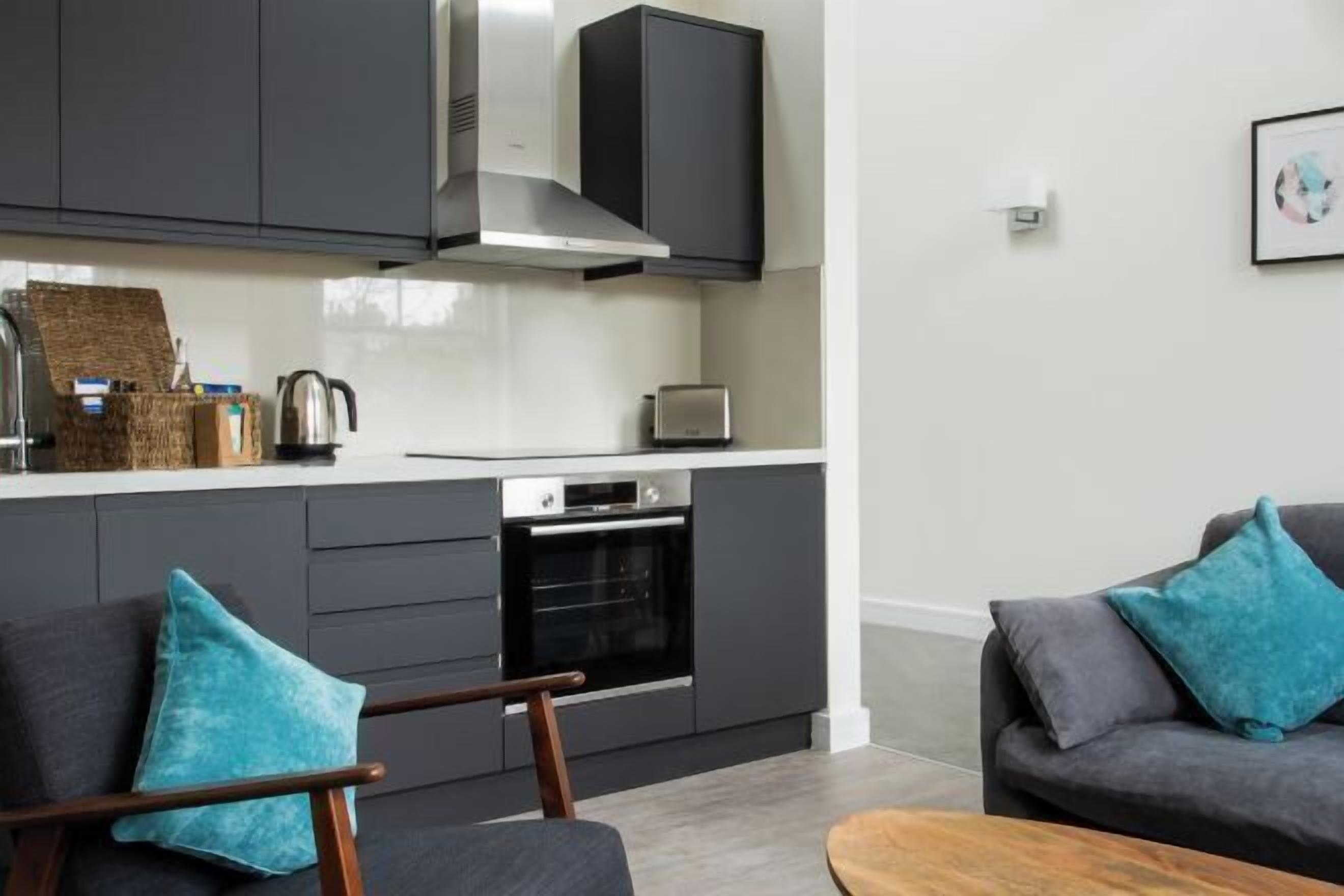A modern kitchen with dark cabinetry, a built-in oven, and a toaster.