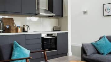 A modern kitchen with dark cabinetry, a built-in oven, and a toaster.