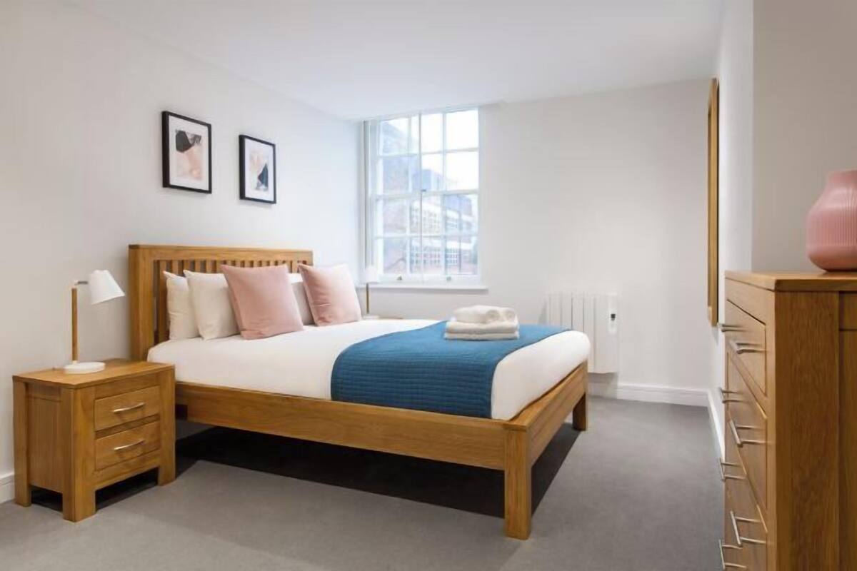 Une chambre à coucher avec un lit en bois, des tables de chevet, une fenêtre et une commode.