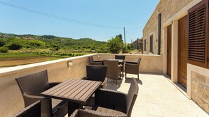 Une terrasse extérieure aménagée avec des meubles en osier et offrant une vue sur un vignoble.