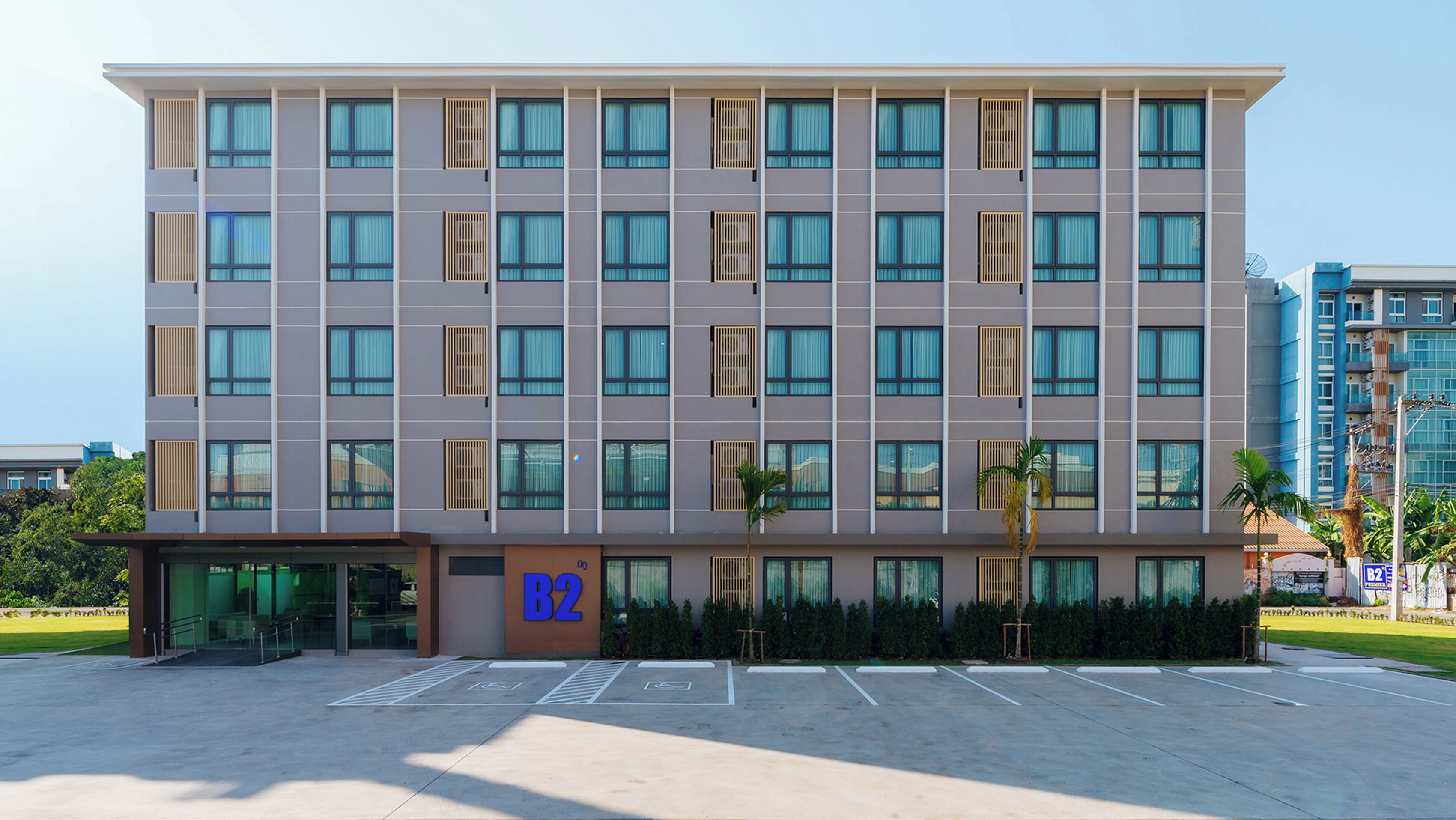 A multi-story hotel with a modern facade, large windows, and a parking lot in front.