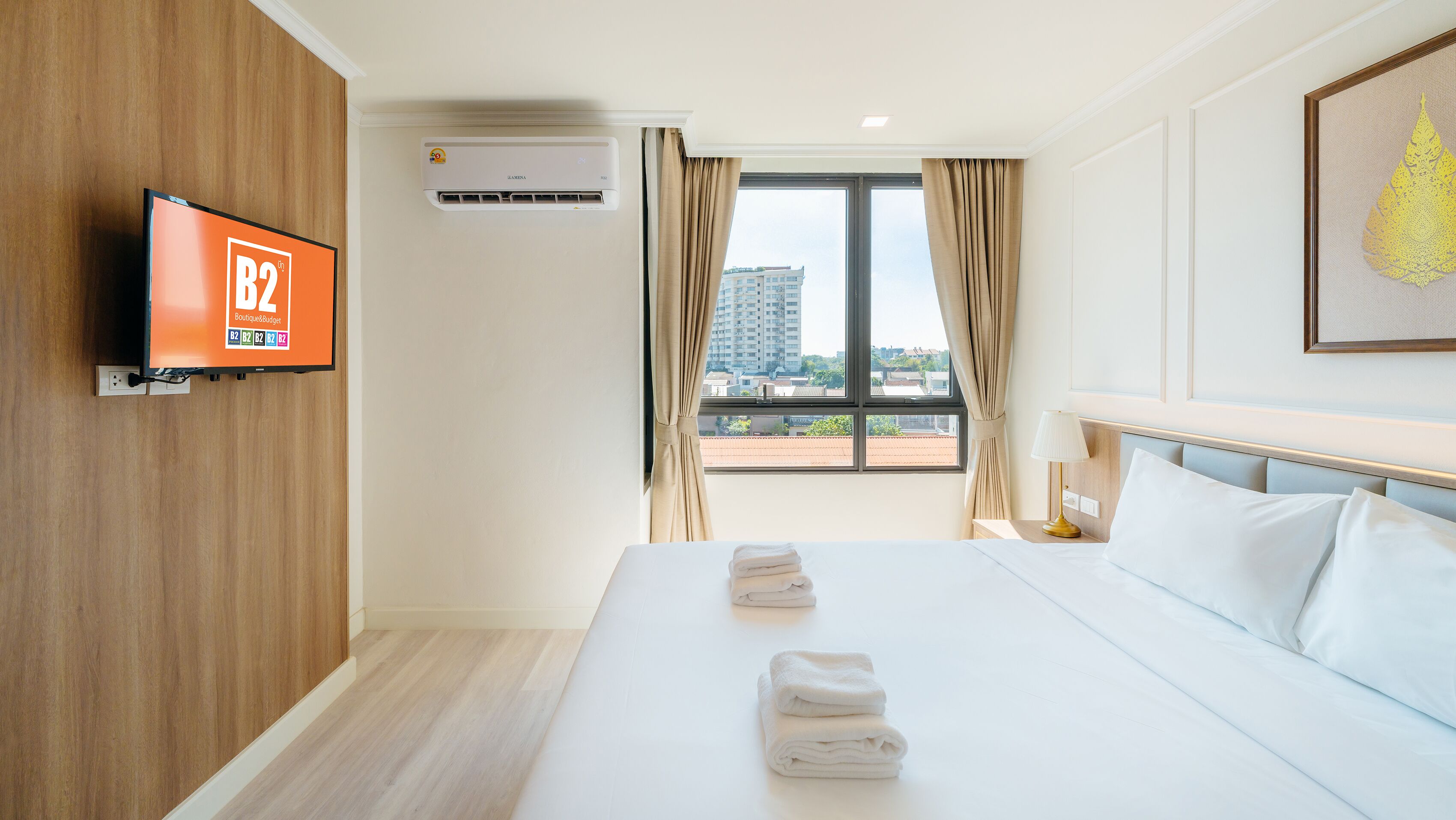 A hotel room with a bed, a TV, an air conditioner, and a window with curtains.