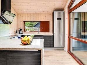 A modern kitchen with a wooden ceiling, stainless steel appliances, and a large window. - 5 Star Holiday Home in Vaeggerlose (Vaeggerlose)