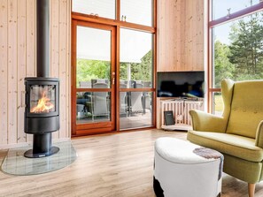 A modern living room with a wood-burning stove, a television, and a comfortable seating area. - 5 Star Holiday Home in Vaeggerlose (Vaeggerlose)