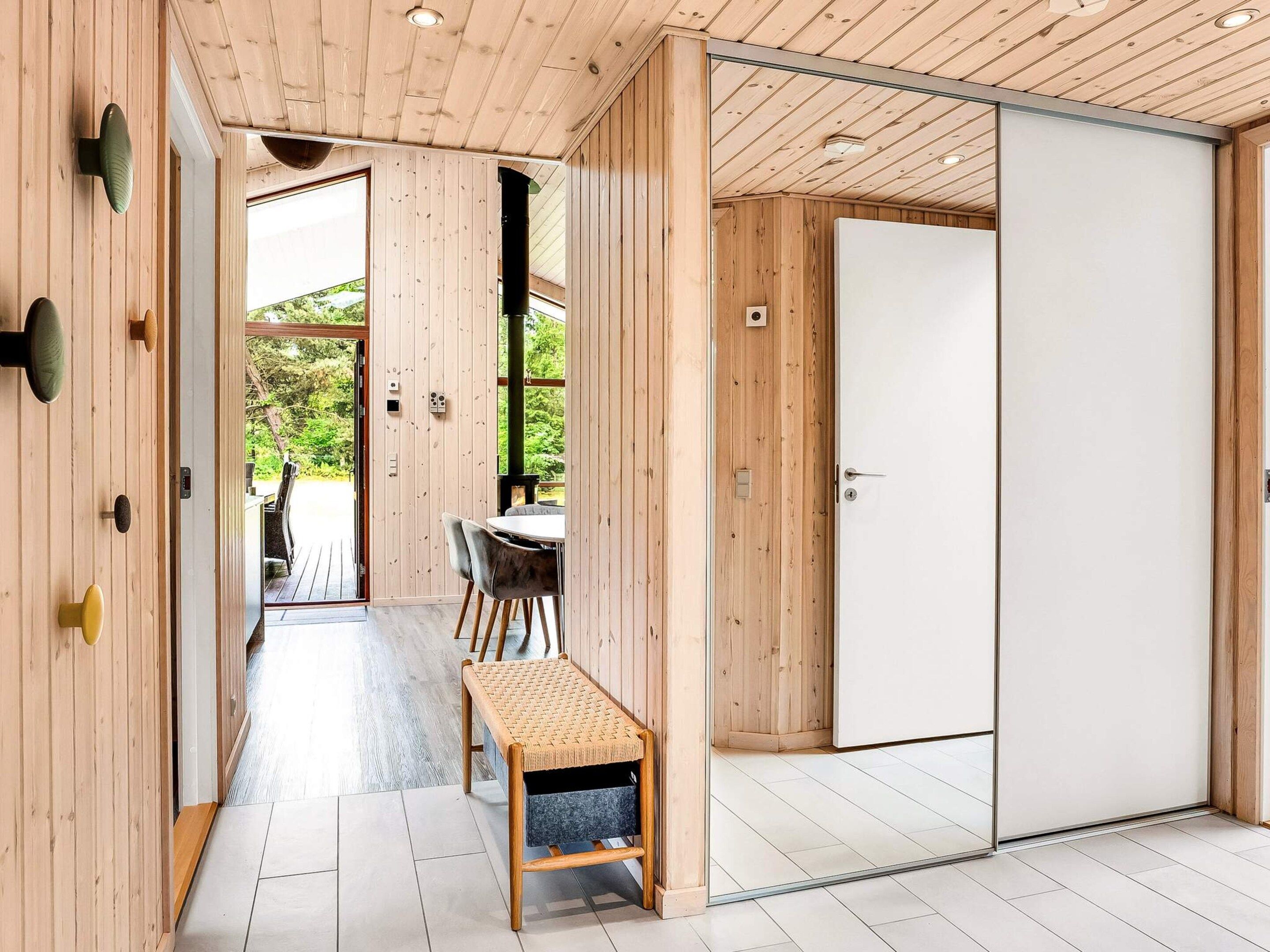 A wooden interior with a sliding door, a bench, and a table with chairs.