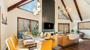 A dining area with a wooden table, yellow chairs, and a modern chandelier. - Slope View Chalet Hot Tub, Firepit, Family Fun (McGaheysville)