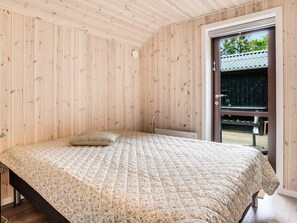 A bedroom with a bed, a wooden ceiling, and a door leading outside. - 5 Star Holiday Home in Vaeggerlose (Vaeggerlose)