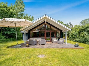 Une maison moderne dotée d’un patio couvert, d’un espace salon extérieur et d’un grand parasol.