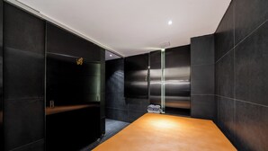 A modern bathroom with dark tiles, a wooden vanity, and a towel rack. - Yeoksam Lumiere (Seoul)