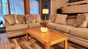 Ein Wohnzimmer mit einem Holztisch, beigen Sofas und einer Blumenvase.