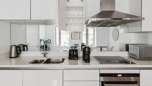 A modern kitchen with white cabinetry, stainless steel appliances, and a central island with a sink and coffee maker.