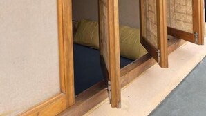 Una habitación japonesa tradicional con suelo de tatami, una cama de madera baja y puertas correderas shoji.