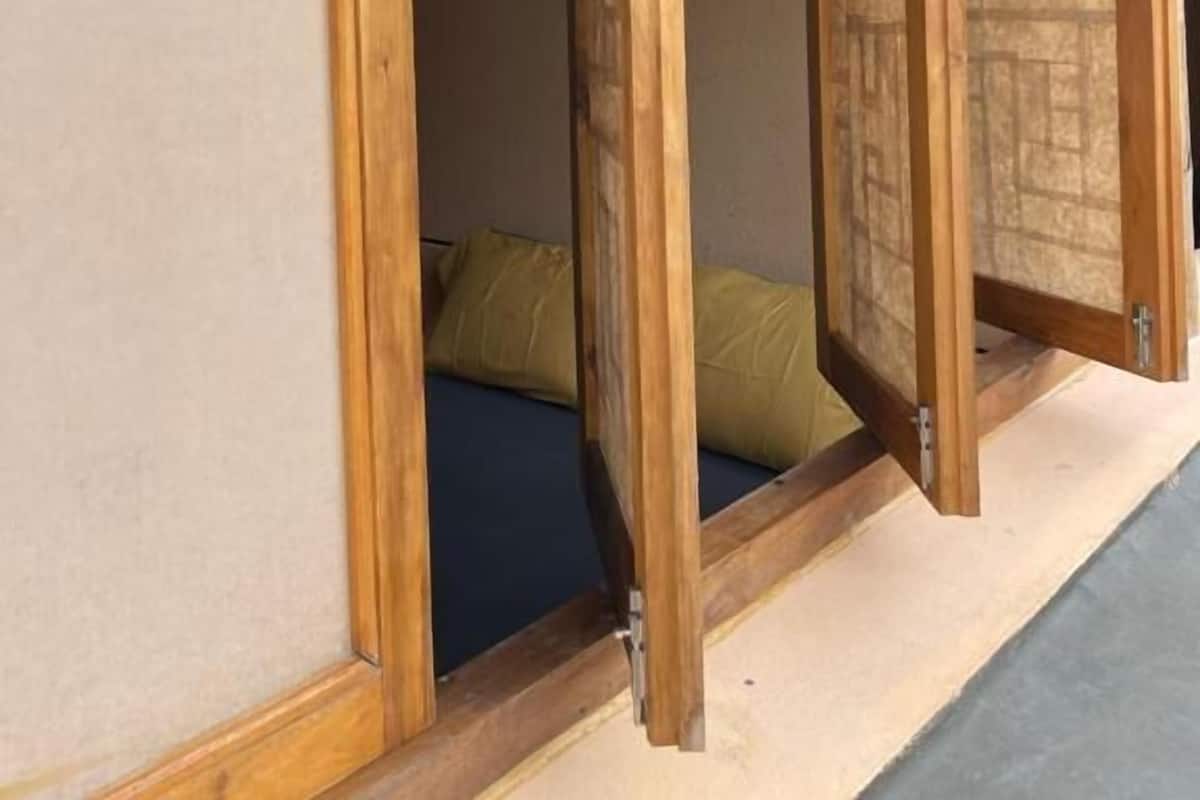 A traditional Japanese room with tatami flooring, a low wooden bed, and sliding shoji screens.