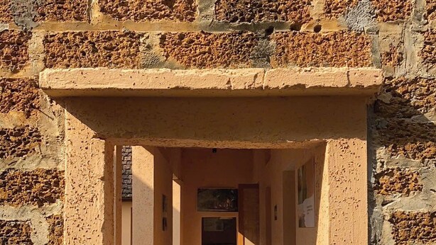 Un pasillo con piso de baldosas y pared de piedra a un lado.