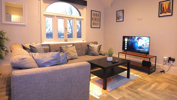 A living room with a sofa, coffee table, TV, and a window with curtains. - The Hampstead Hideaway (London)