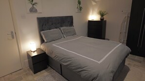 A bedroom with a bed, nightstands, a door, and wall art. - The Hampstead Hideaway (London)