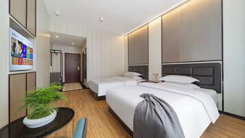 A hotel room with a bed, bedside tables, a TV, and a potted plant.