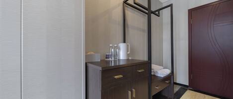A modern hotel room with a wooden cabinet, a mirror, and a dark wooden door.