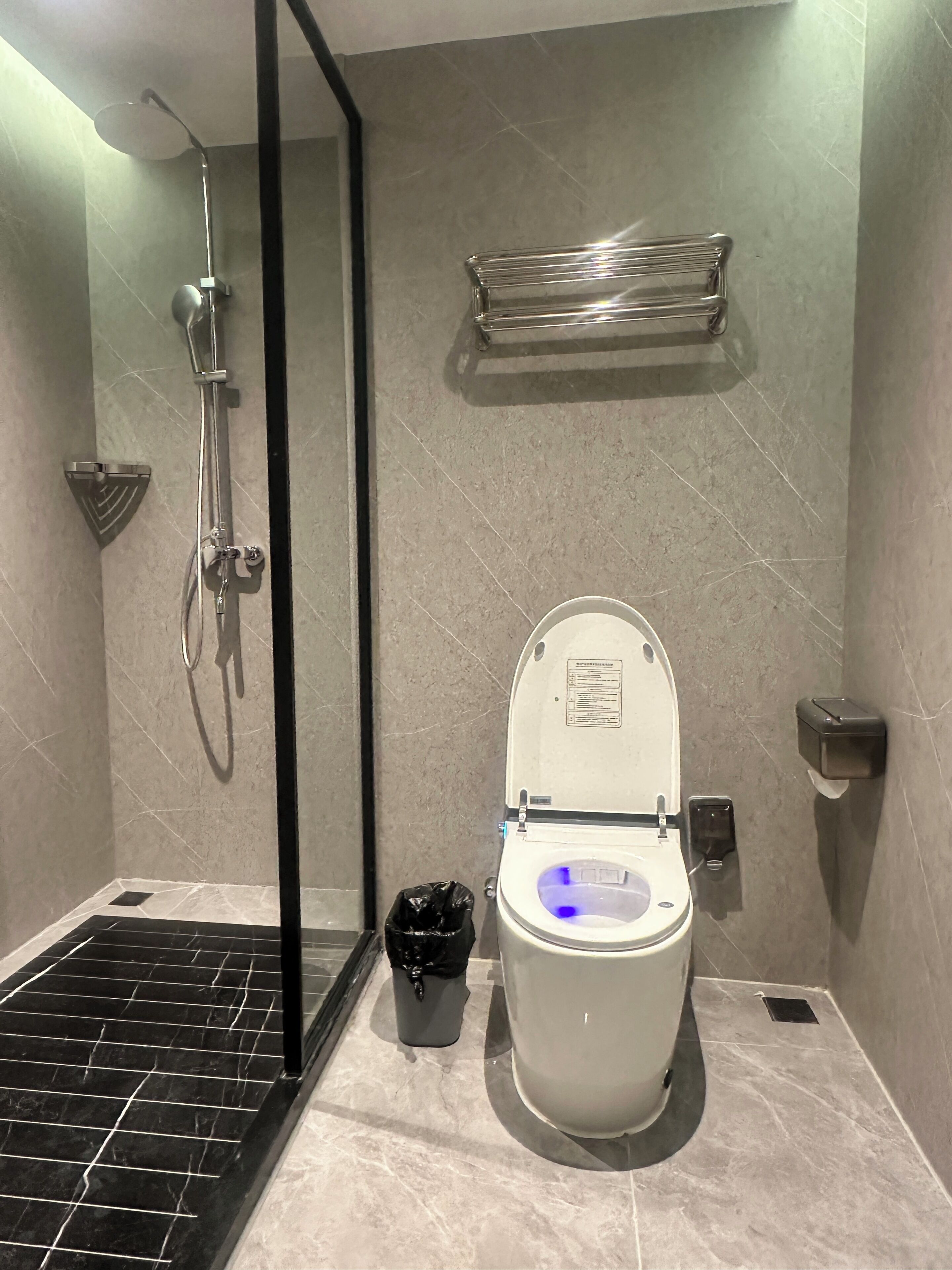 Ein Badezimmer mit Dusche, Toilette und Mülleimer.