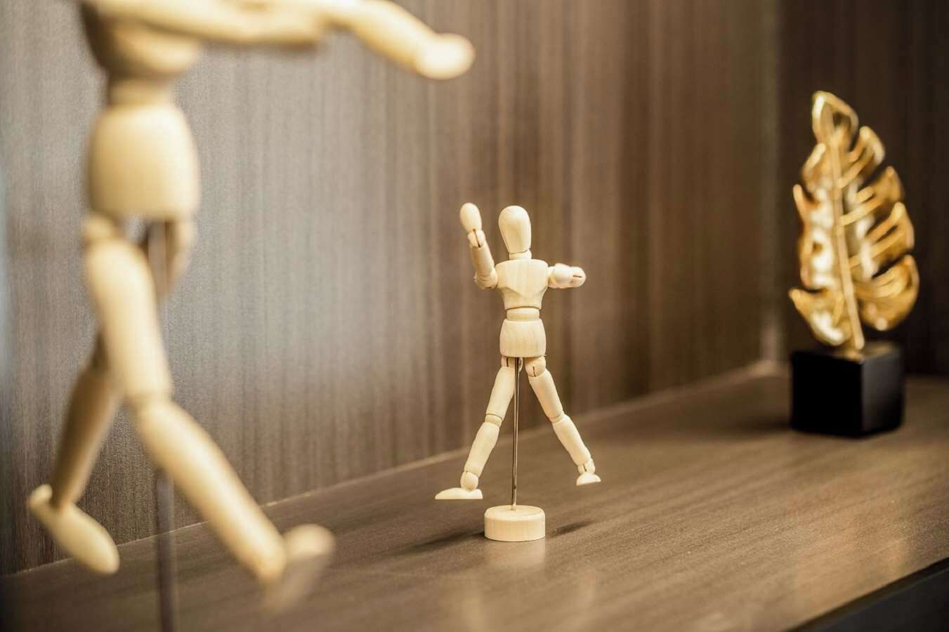 Un maniquí de madera en un estante con un adorno dorado.