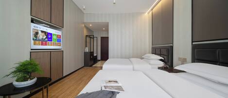 A modern hotel room with a large bed, a bedside table, a TV mounted on the wall, and a potted plant.