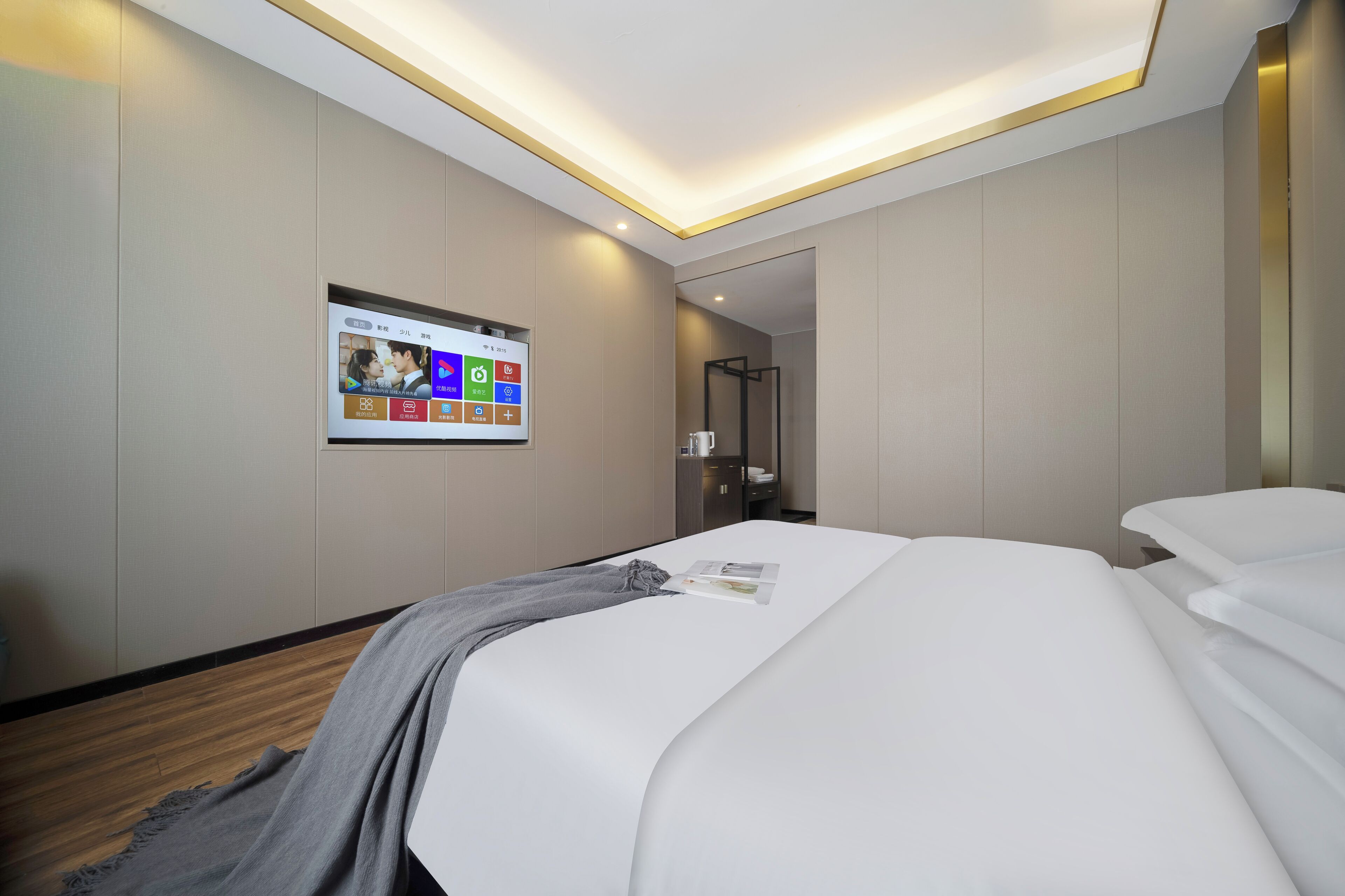 Une chambre d’hôtel avec un lit, un téléviseur fixé au mur qui affiche une application de l’hôtel et un plancher en bois.