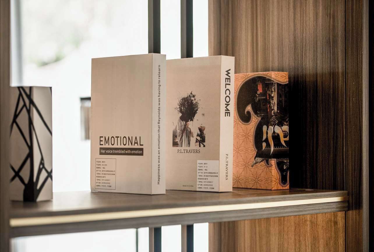 Three books on a shelf with titles 'EMOTIONAL,' 'PLITRAVERS,' and 'WELCOME.'