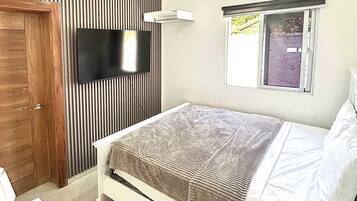 Une chambre à coucher comprenant un lit, un téléviseur, un ventilateur de plafond et un appareil de climatisation.
