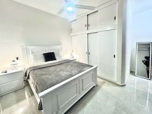 Une chambre à coucher comprenant un lit, des tables de chevet, une armoire et un miroir.