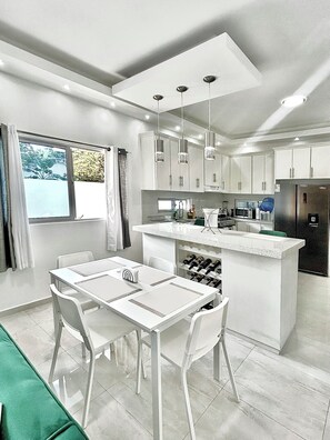 A modern kitchen with white cabinetry, a central island with a sink, and pendant lighting.